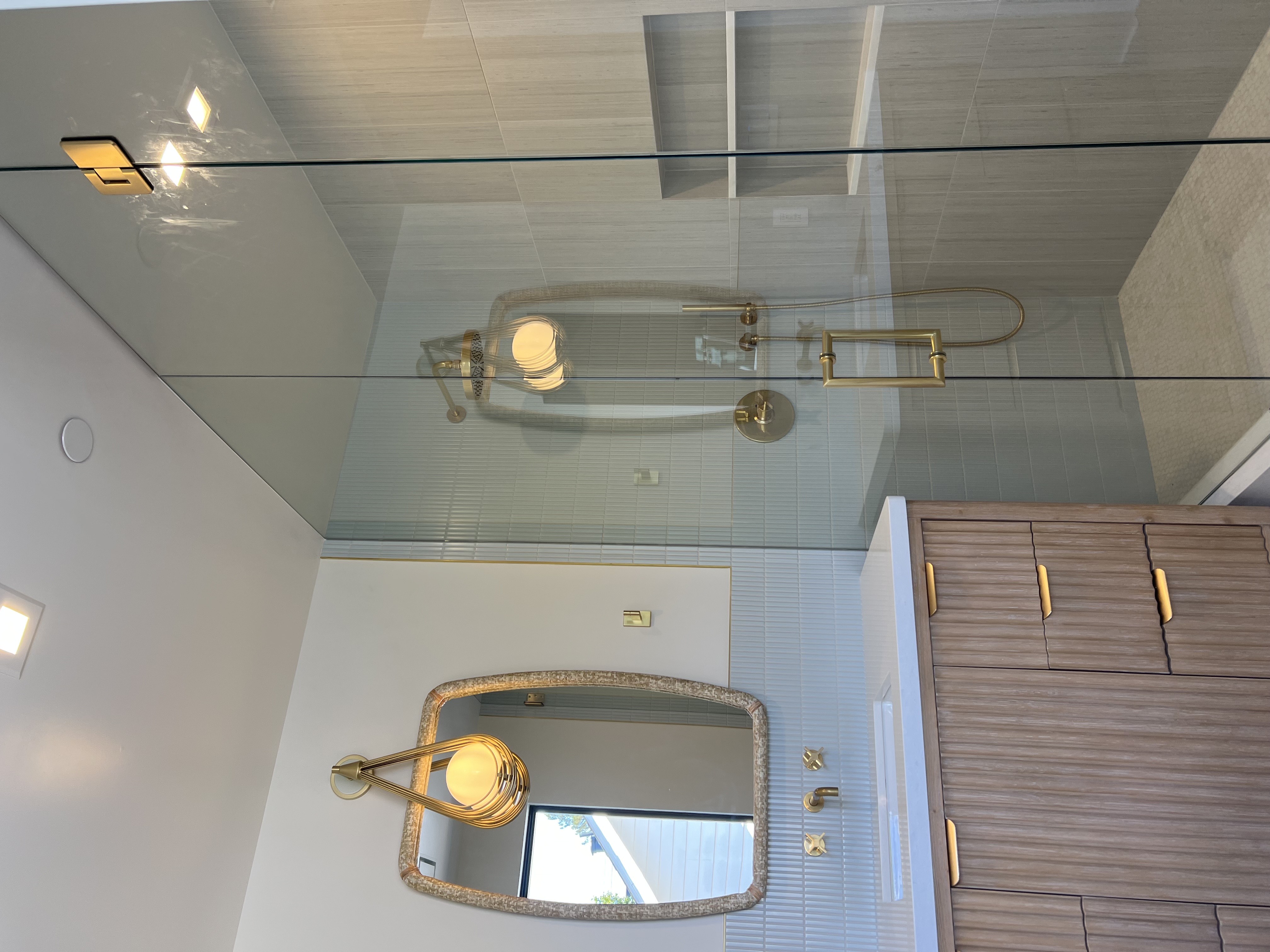 Vanity and shower with gold fixtures and ribbed cabinetry