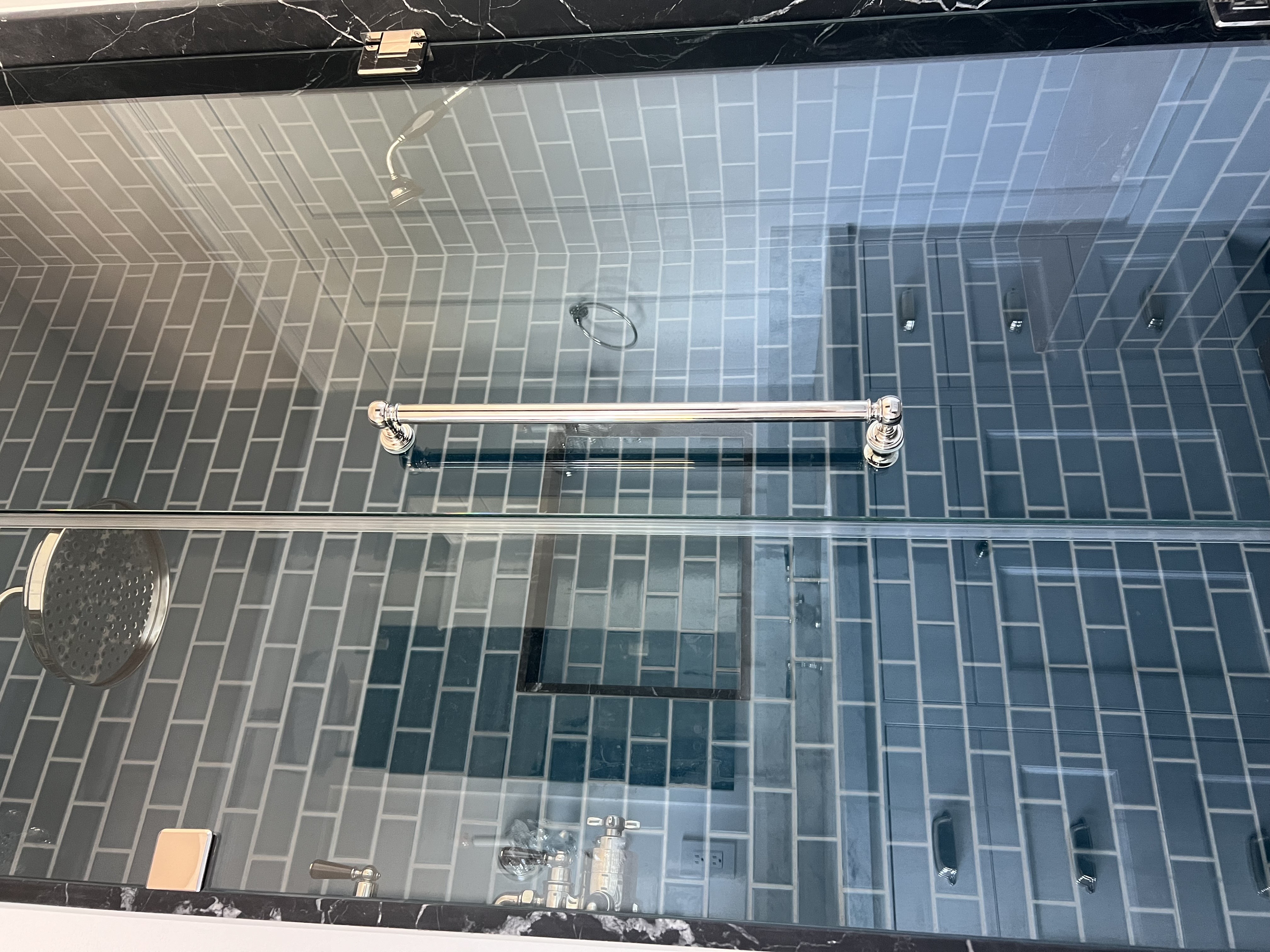Blue tile shower with glass door and chrome hardware
