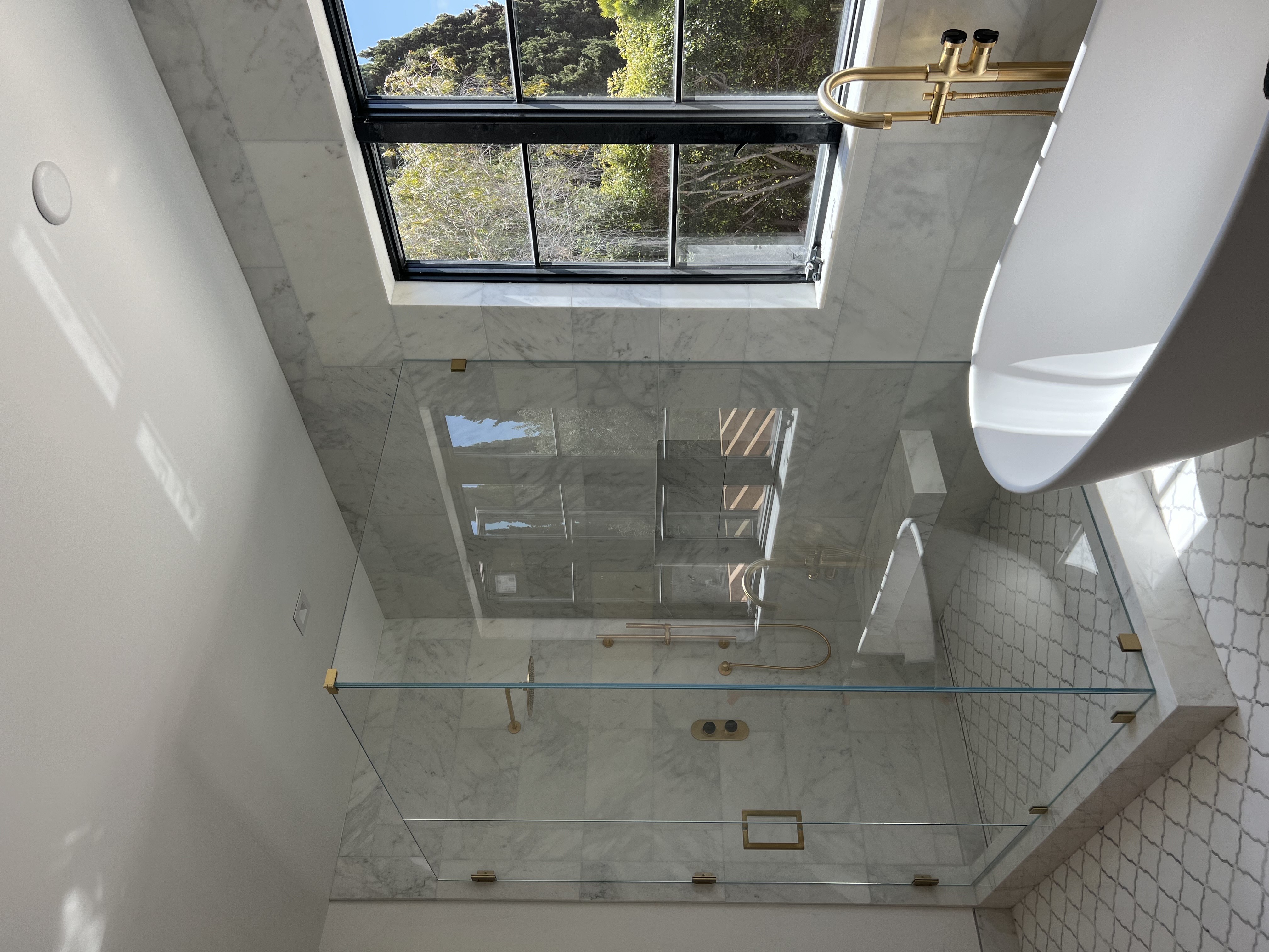 Corner frameless shower with brass details