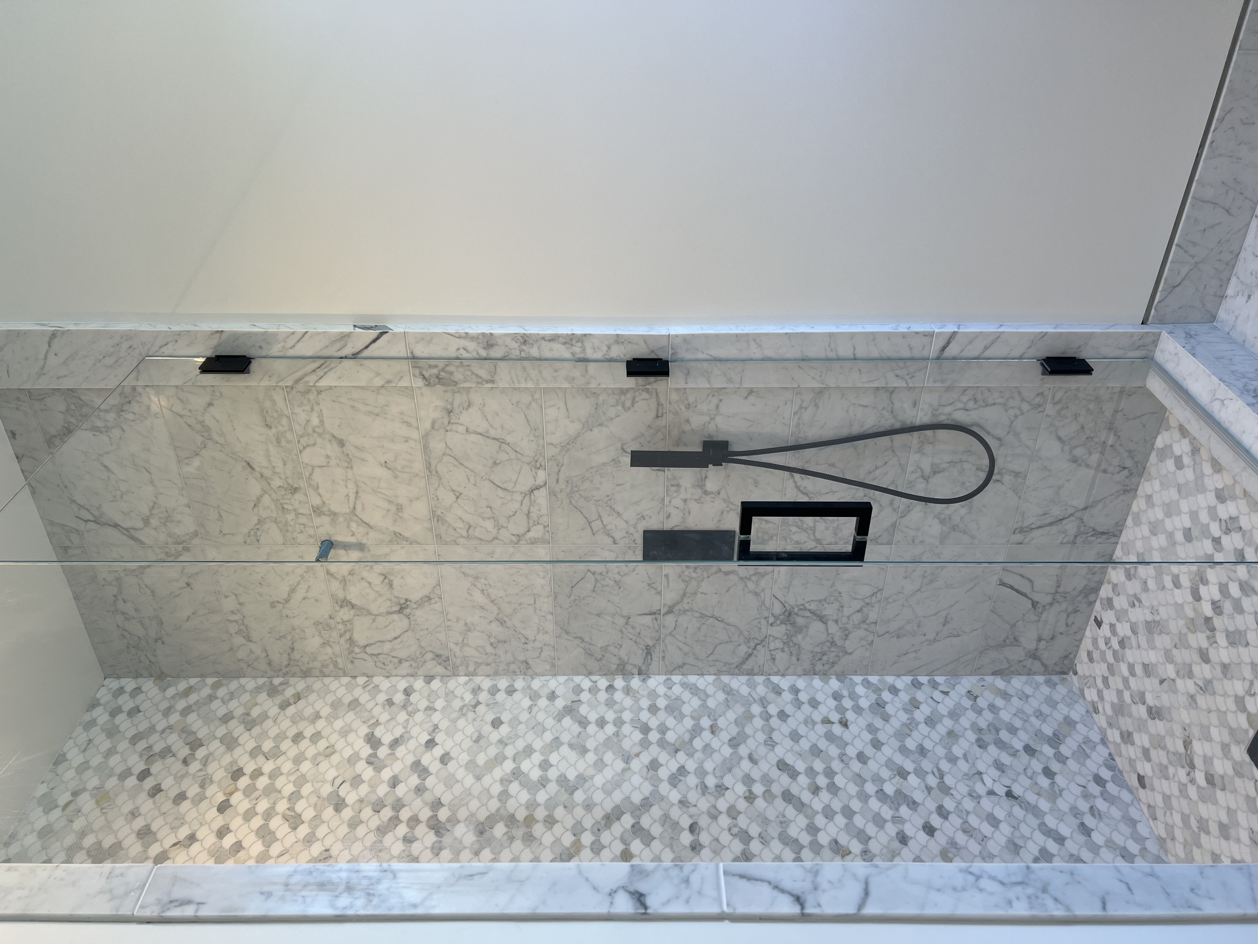 Frameless shower enclosure with patterned tile